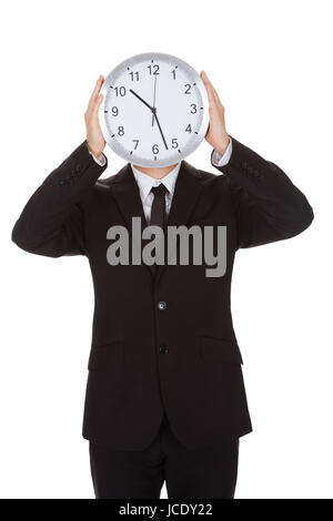 Businessman holding réveil sur le visage. Isolated on white Banque D'Images