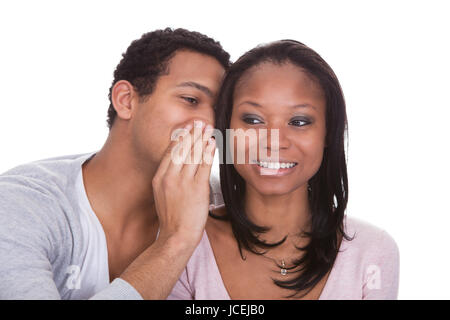 Homme murmurant à l'oreille de petite amie sur fond blanc Banque D'Images