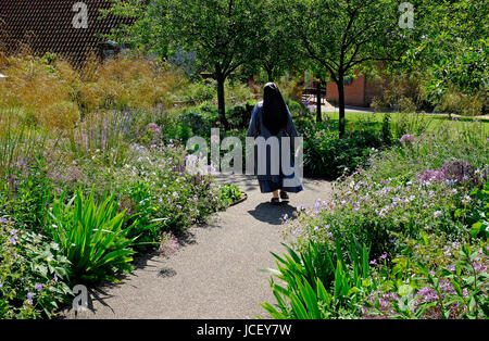 Nun walking in jardins à peu de Walsingham, North Norfolk, Angleterre Banque D'Images