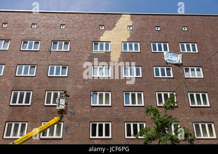 L'artiste Boran Burchhardt photographies couleur bleu des taches sur la façade de la maison dans le quartier de Veddel, Hambourg, Allemagne, 15 juin 2017. Deux jours seulement après le début de l'art projet "Veddel doré' des inconnus ont enduit le mur avec de la peinture. L'artiste a commencé le mur Burchardt placage façade avec de l'or sur le 13 juin 2017. Photo : Daniel Bockwoldt/dpa Banque D'Images