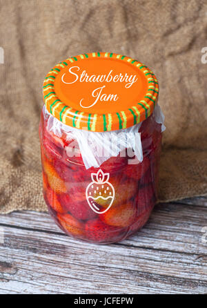Confiture de fraise en pot avec ruban isolé sur fond de bois Banque D'Images