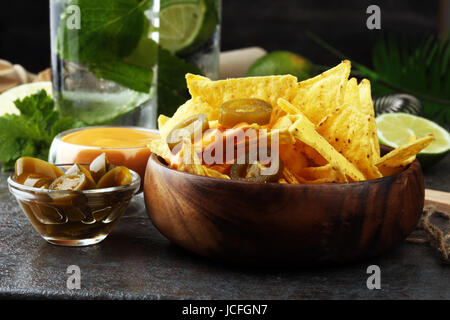 Un plateau de nachos tortillas avec de la sauce au fromage fondu sur fond sombre Banque D'Images