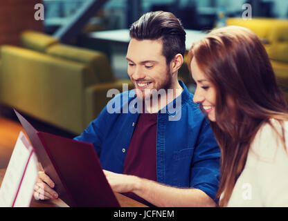 Smiling couple avec des menus au restaurant Banque D'Images