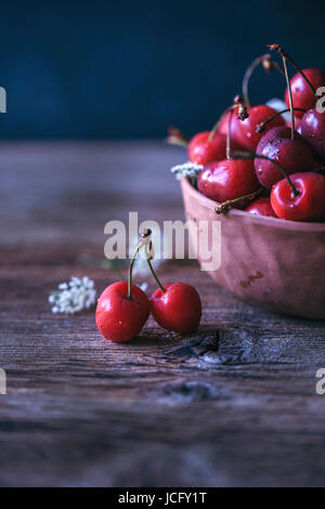 Cerises fraîches dans un bol en céramique sur une table en bois rustique Banque D'Images