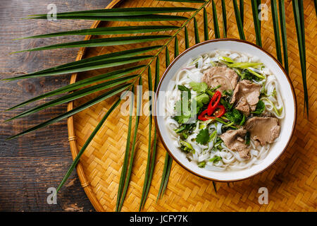 Pho Bo soupe vietnamienne à base de boeuf sur le plateau de bambou sur fond de bois Banque D'Images