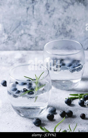 Eau Tonique cocktail avec le romarin et les bleuets. Deux verres plus froid gris bleu texture background. Boisson rafraîchissante sans alcool de l'alco Banque D'Images