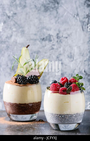 Petit-déjeuner dessert diverses couches chia seeds, chocolat au lait, bouillie de riz dans le verre décoré par des mûres fraîches, des tranches de poire, de poudre de cacao. St Banque D'Images