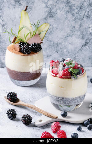 Petit-déjeuner dessert diverses couches chia seeds, chocolat au lait, bouillie de riz dans le verre décoré par des mûres fraîches, des tranches de poire, de poudre de cacao. Sur Banque D'Images