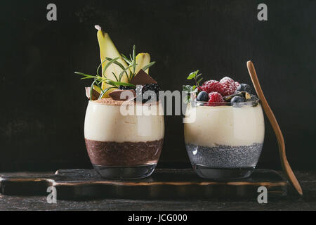 Petit-déjeuner dessert diverses couches chia seeds, chocolat au lait, bouillie de riz dans le verre décoré par des mûres fraîches, des tranches de poire, de poudre de cacao. Sur Banque D'Images