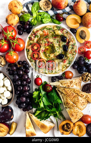 L'aubergine babaganoush avec poivron rouge et d'herbes sur une carte snack plein de fruits d'été photographiés en vue de dessus. Banque D'Images