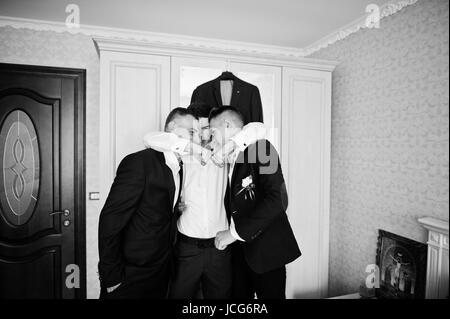 Beau palefrenier et groomsman en chambre hugging à côté du miroir. Banque D'Images