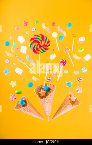 Close-up Vue de dessus des cônes alvéolés et mélange de diverses sucreries sur fond jaune Banque D'Images