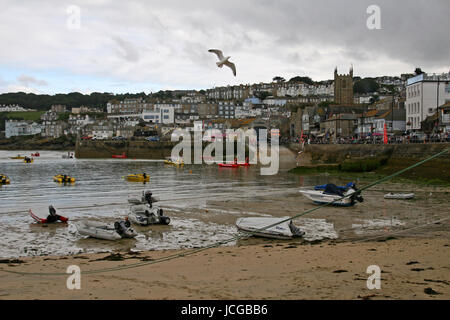 Approches tempête St Ives harbour Cornwall. Un oiseau vole et bateaux sont amarrés à marée montante, comme avec ciel bleu à distance derrière les nuages gris et blanc Banque D'Images