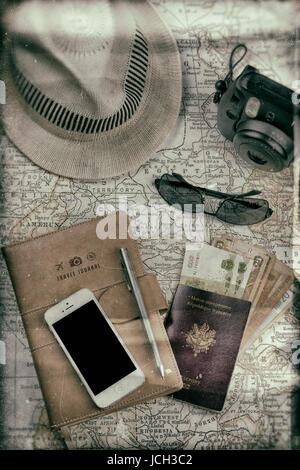 Configuration vintage avec une carte ancienne, appareil photo instantané, téléphone à écran noir, lunettes de soleil, devises, et chapeau blanc, évoquant une sensation nostalgique, concept de voyage Banque D'Images