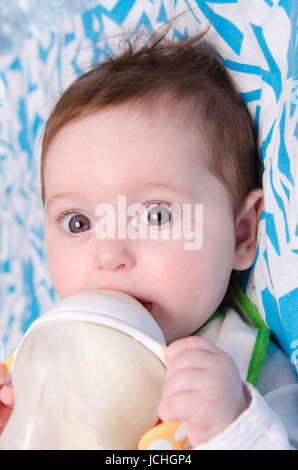 Six mois du lait de consommation à partir d'une bouteille avec la tétine Banque D'Images