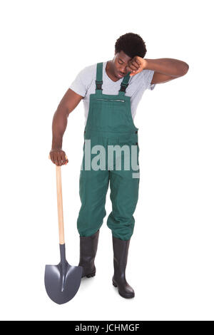 Jardinier homme fatigué Holding Shovel sur fond blanc Banque D'Images