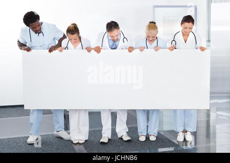 Groupe de professionnels Médecins multiraciale Holding Placard en clinique Banque D'Images