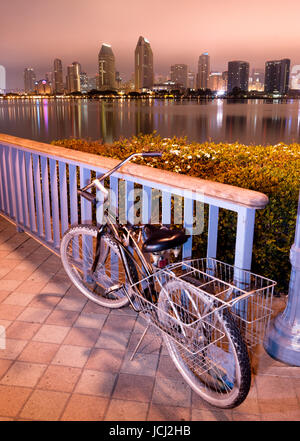 Un vélo est verrouillé à la clôture à Coronado à San Diego dans l'arrière-plan dans la nuit Banque D'Images