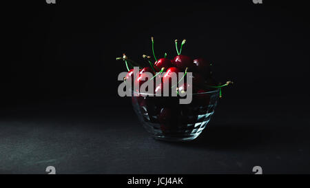 Les cerises dans une plaque transparente sur fond noir Banque D'Images