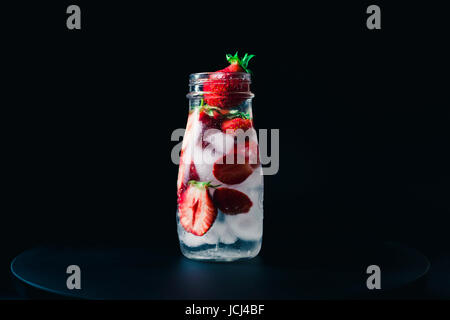 L'eau infusée aux fraises avec de la glace sur un fond noir. Banque D'Images