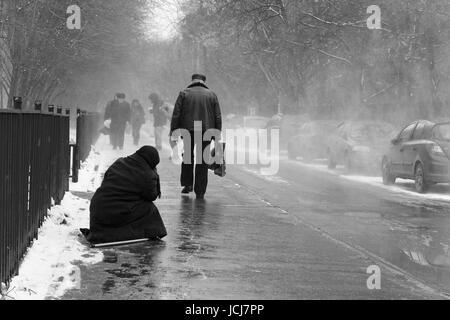 Moscou, Russie, le 24 mars 2011 : La vieille femme demande l'aumône, assis sur le trottoir pendant la tempête de neige. Banque D'Images