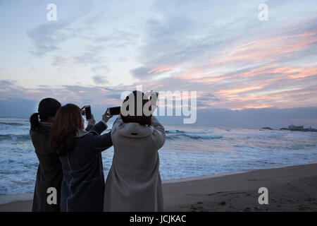 Retour de trois femmes d'âge moyen en tenant sur la plage au lever du soleil selfies Banque D'Images