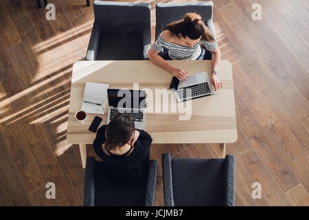 L'entreprise de démarrage et la technologie mobile nouveau concept avec jeune couple dans un style moderne aux couleurs vives de l'intérieur de bureau travaillant sur ordinateur portable et tablette ordinateur sur nouveau projet créatif et de remue-méninges, antenne vue d'en haut. Banque D'Images