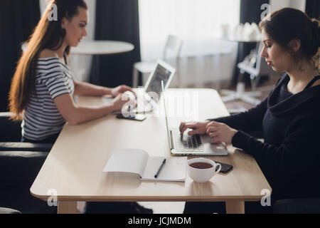 Concept de démarrage d'entreprise avec deux jeunes filles dans un style moderne aux couleurs vives de l'intérieur de bureau travaillant sur des ordinateurs portables et tablettes électroniques sur nouveau projet créatif et de remue-méninges, antenne vue d'en haut. Banque D'Images