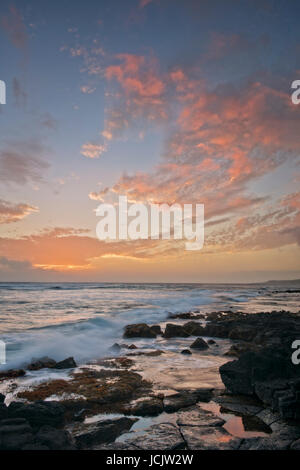 Fiery coucher du soleil enflamme le ciel au-dessus de la rive sud à Poipu sur l'île de Kauai. Banque D'Images