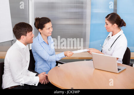 Happy Young Couple Giving Enveloppe pour femme médecin Banque D'Images