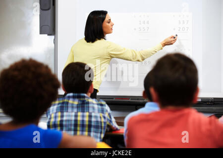 Teacher Standing In classe à l'aide du tableau blanc interactif Banque D'Images