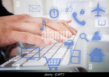 Portrait of businessman typing on computer keyboard avec diverses icônes vectorielles Banque D'Images