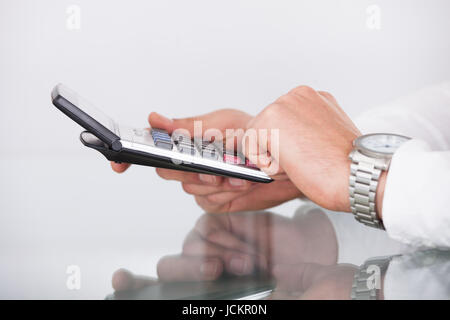 Portrait of woman's hands using calculator at office desk Banque D'Images