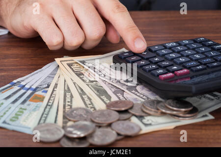 Portrait of businessman using calculator avec pièces et billets en euros sur 24 Banque D'Images