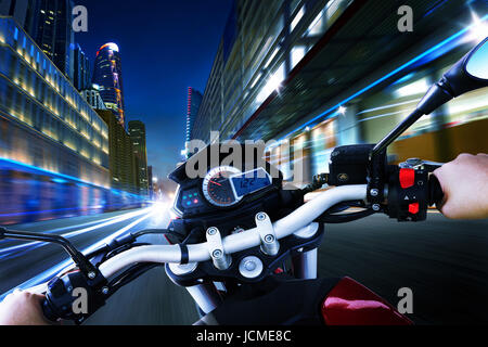 La conduite d'une moto motard rides le long de la rue de ville , scène de nuit . Angle de vue à la première personne . Banque D'Images