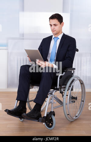 Longueur totale de mobilité businessman using digital tablet in office fauteuil roulant sur Banque D'Images