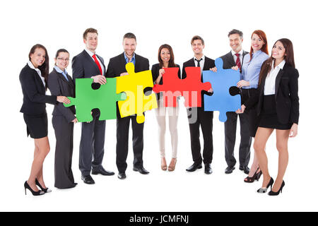 Groupe de businesspeople holding quatre grandes pièces de puzzle de couleur vive de conceptuel d'équipe dans la résolution d'un problème d'affaires ou réunion un défi isolated on white Banque D'Images