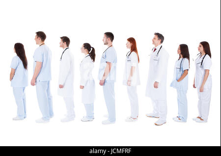 Grand groupe diversifié de personnel médical en uniformes blancs avec stéthoscope autour du cou debout dans une file d'attente dans le profil l'un derrière l'autre sur l'image isolated on white Banque D'Images