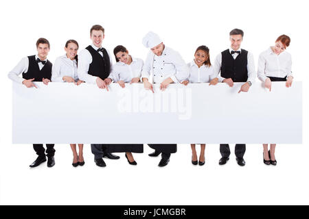 Grand groupe de personnel de restauration holding a blank banner with copyspace pour votre texte, y compris un chef serveurs serveuses hôtesse et steward vin isolated on white Banque D'Images