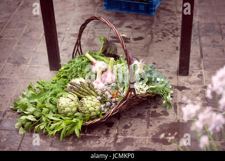 Panier de légumes fraîchement cueillis y compris les artichauts, l'ail et les asperges dans une serre UK Banque D'Images