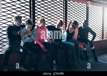 Photo de jeunes adultes d'athlétisme dans les vêtements de sport et de rire, assis contre la fenêtre. Banque D'Images