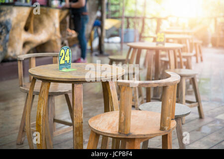 Tour des tables et des chaises en bois de style ancien avec le numéro à l'intérieur piscine restaurant local le matin. Banque D'Images