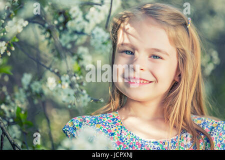 Happy little girl playing in spring cherry garden Banque D'Images