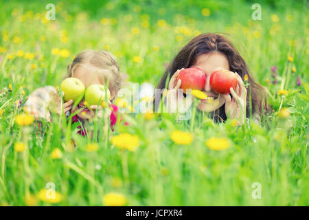 Mother and Daughter lying on pré vert et holding apples Banque D'Images