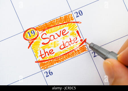 Femme doigts avec stylo rouge écrit Save the Date de rappel. Banque D'Images