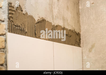 Le céramiste appliqué sur le mur de ciment à carrelage, beau carrelage dans la salle de bains Banque D'Images