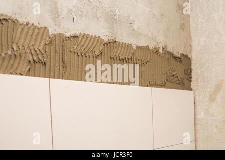 Le céramiste appliqué sur le mur de ciment à carrelage, beau carrelage dans la salle de bains Banque D'Images