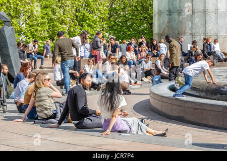 Londres, Royaume-Uni - 10 mai 2017 - Cabot Square à Canary Wharf bondés de gens assis et bavardant sur une journée ensoleillée Banque D'Images