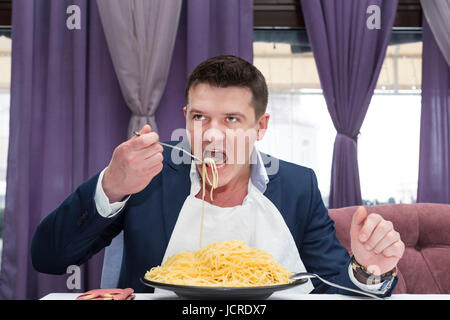 Homme mangeant une grande portion de pâtes dans un restaurant Banque D'Images