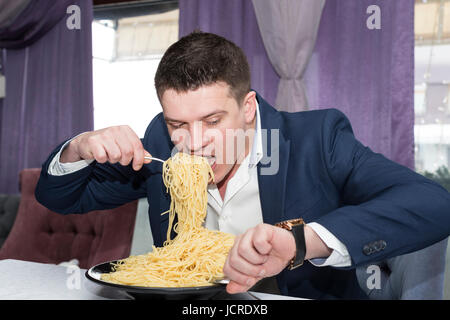 Homme mangeant une grande portion de pâtes dans un restaurant Banque D'Images